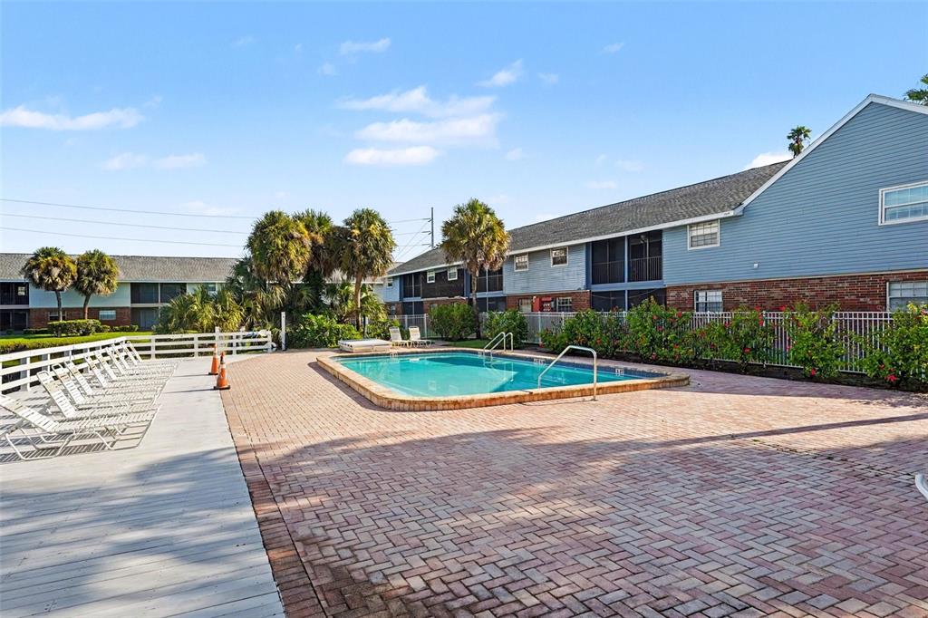 An outdoor swimming pool is surrounded by a brick patio and a white wooden deck — 200 COUNTRYCLUB DRIVE UNIT 1205, LARGO, FL