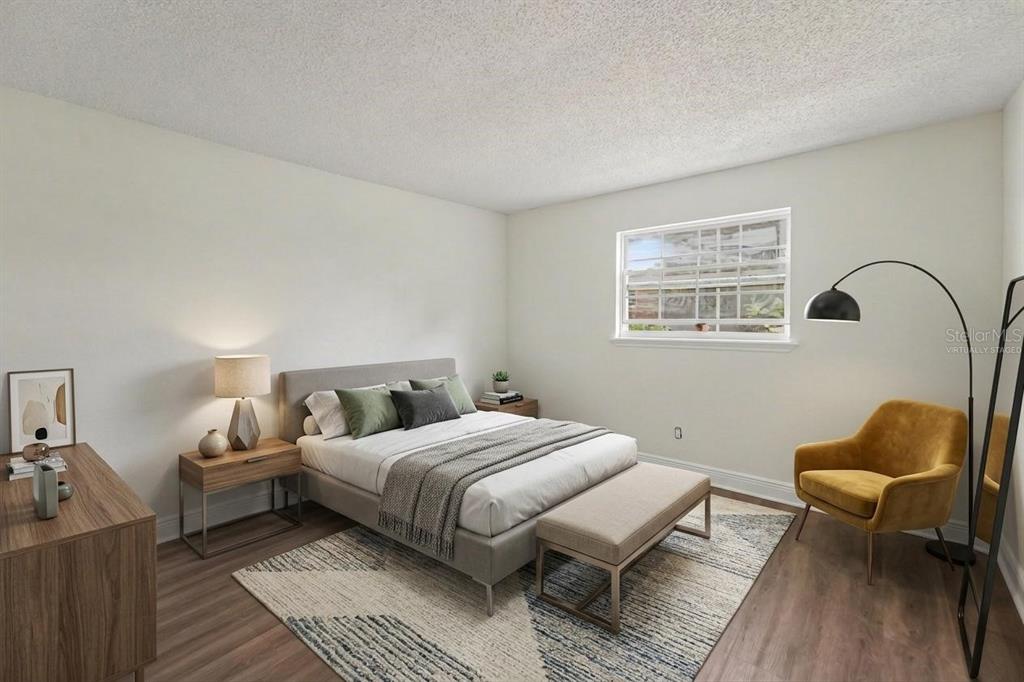 This bedroom features a bed, a yellow armchair, a rug, and wood-look flooring — 200 COUNTRYCLUB DRIVE UNIT 1205, LARGO, FL