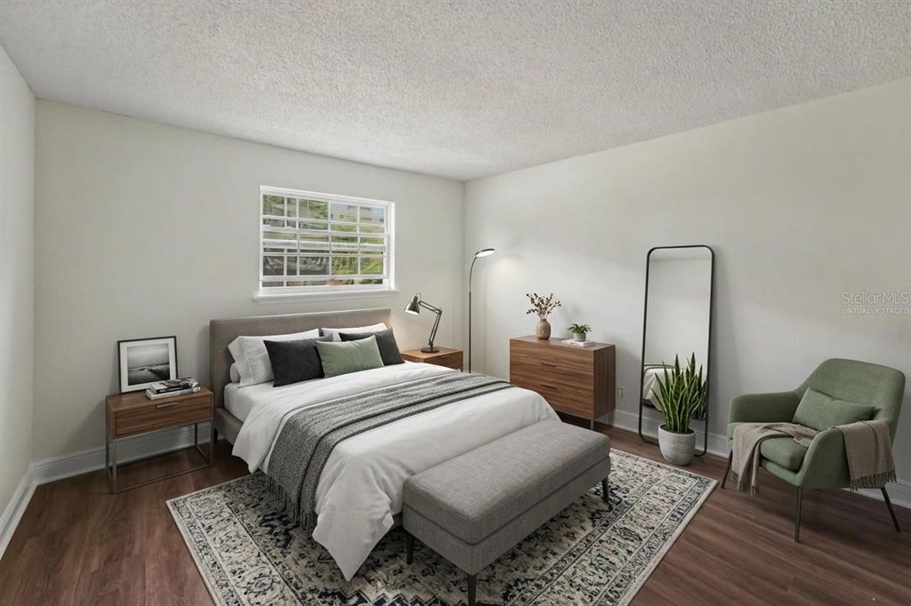A bedroom with a bed, bench, dresser, armchair, and a window with white blinds — 200 COUNTRYCLUB DRIVE UNIT 1205, LARGO, FL