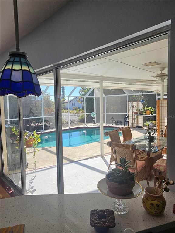 A view from an indoor kitchen counter looking out through sliding doors to a screened pool — 43 WINDSOR DRIVE, ENGLEWOOD, FL