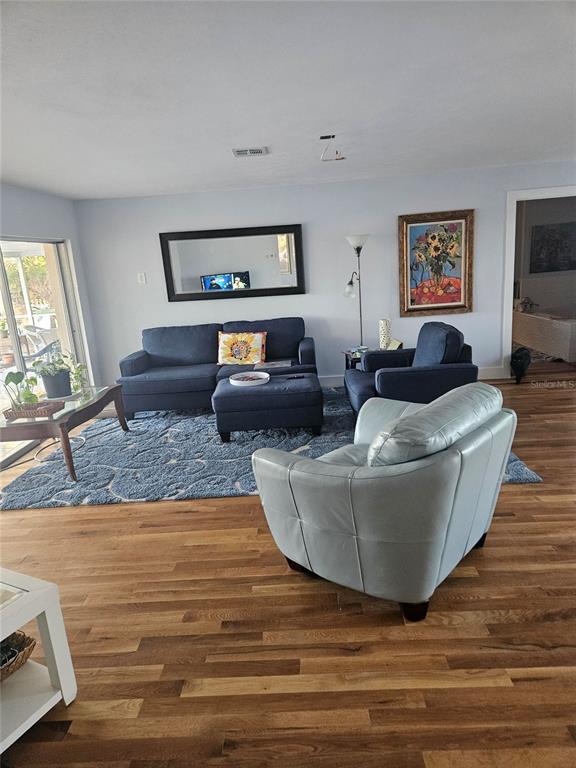 A living room features a blue sofa, matching armchair, light blue accent chair, and hardwood floors — 43 WINDSOR DRIVE, ENGLEWOOD, FL