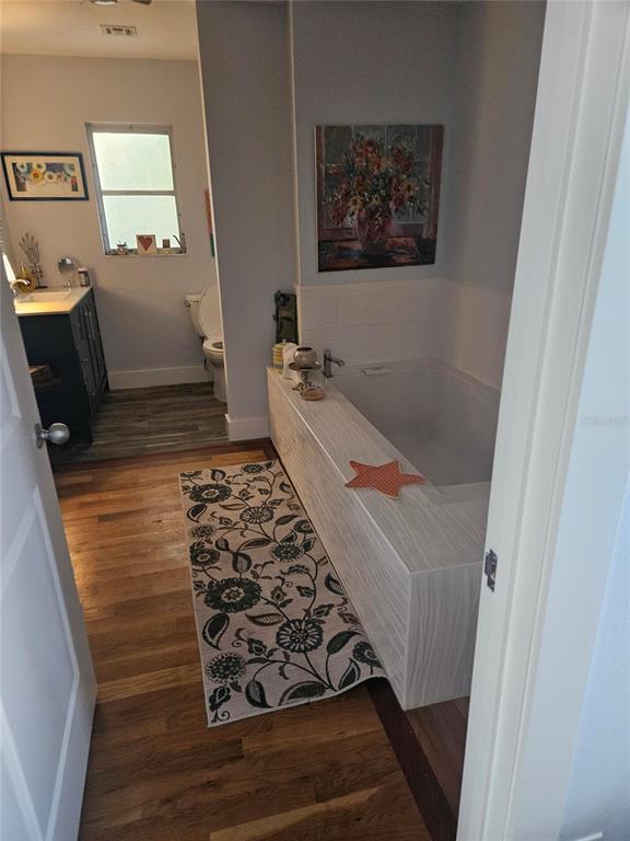 A bathroom features a wood-paneled soaking tub, a floral runner rug, and a separate toilet area — 43 WINDSOR DRIVE, ENGLEWOOD, FL