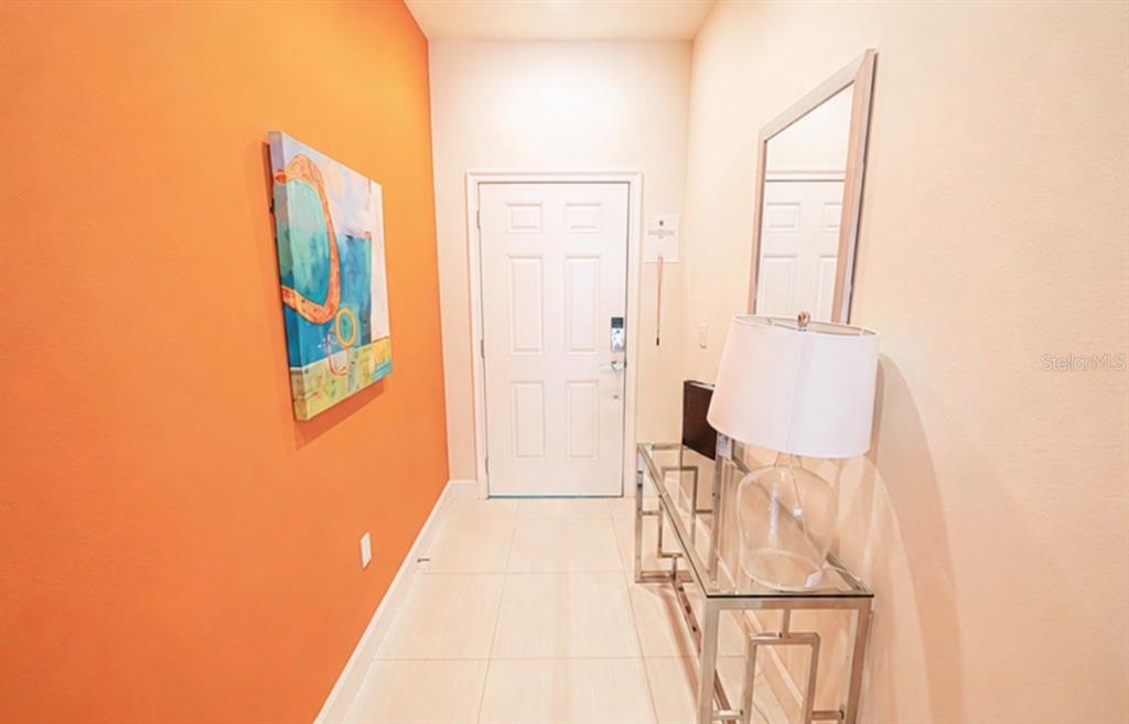 An entryway features an orange accent wall, a white door, and a glass console table — 1603 TRANQUIL AVENUE, CLERMONT, FL