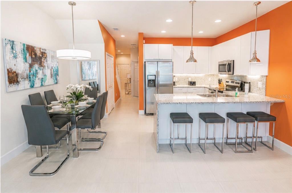 A kitchen and dining area with orange walls, white cabinets, and a granite-topped island — 1603 TRANQUIL AVENUE, CLERMONT, FL