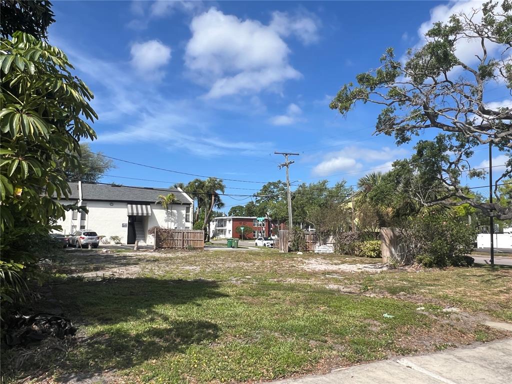 A vacant, grassy lot sits between residential buildings under a bright blue sky — 404 E DAVIS BOULEVARD, TAMPA, FL