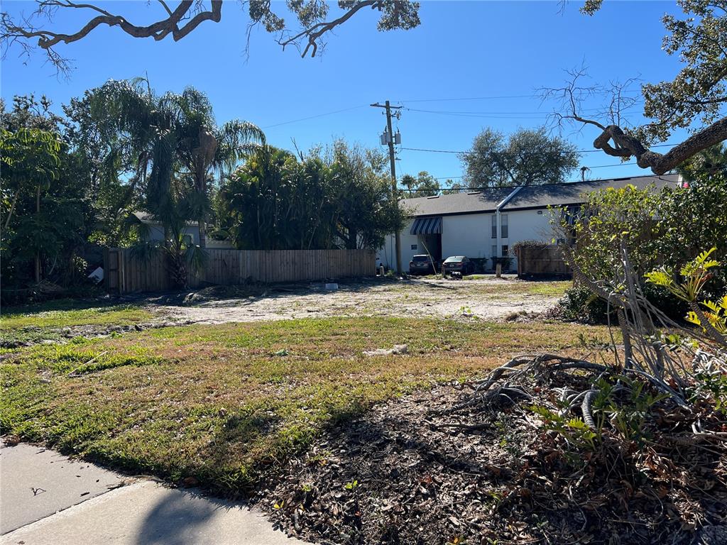 A vacant, grassy residential lot sits in front of a white multi-story building — 404 E DAVIS BOULEVARD, TAMPA, FL