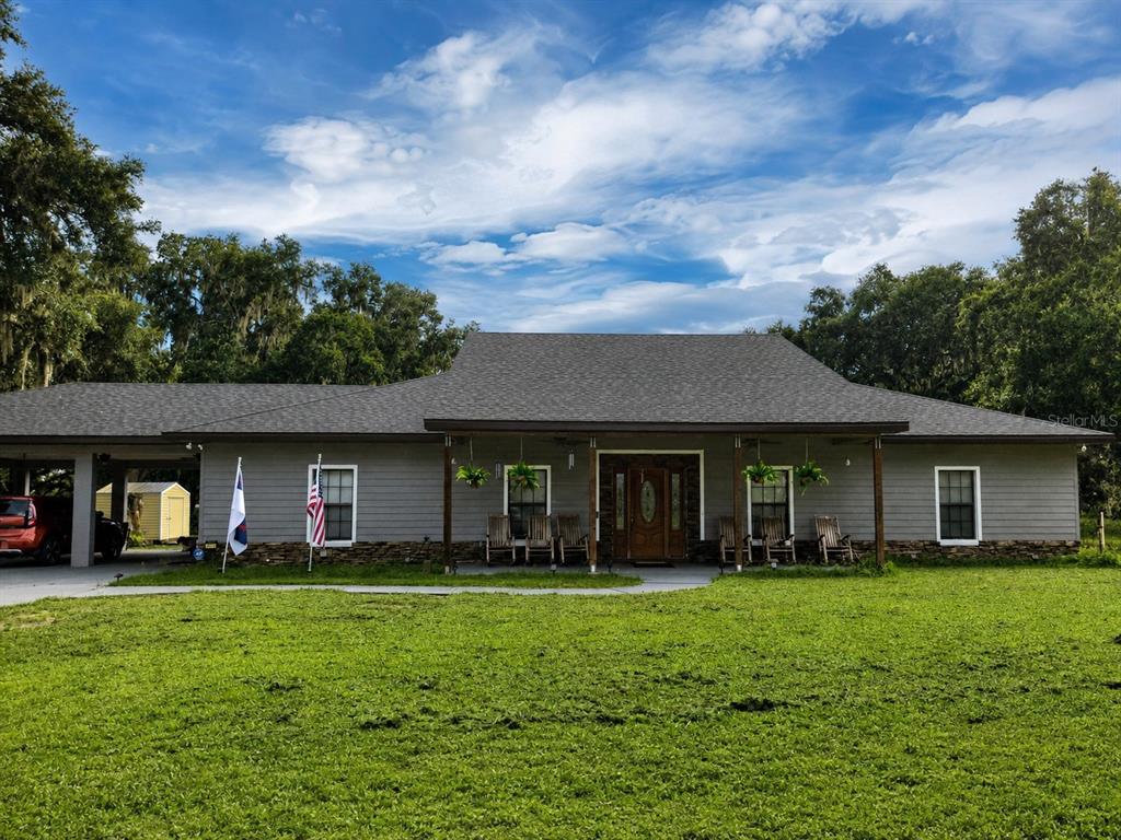 A green single-story house with a dark roof, stone foundation, and a front porch — 2672 SE 35TH STREET, SUMTERVILLE, FL