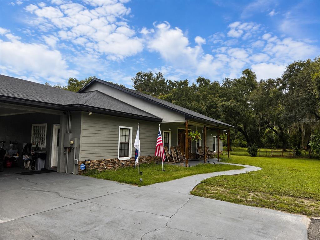 A large, open-sided metal pole barn sits on a grassy lot with a tractor nearby — 2672 SE 35TH STREET, SUMTERVILLE, FL
