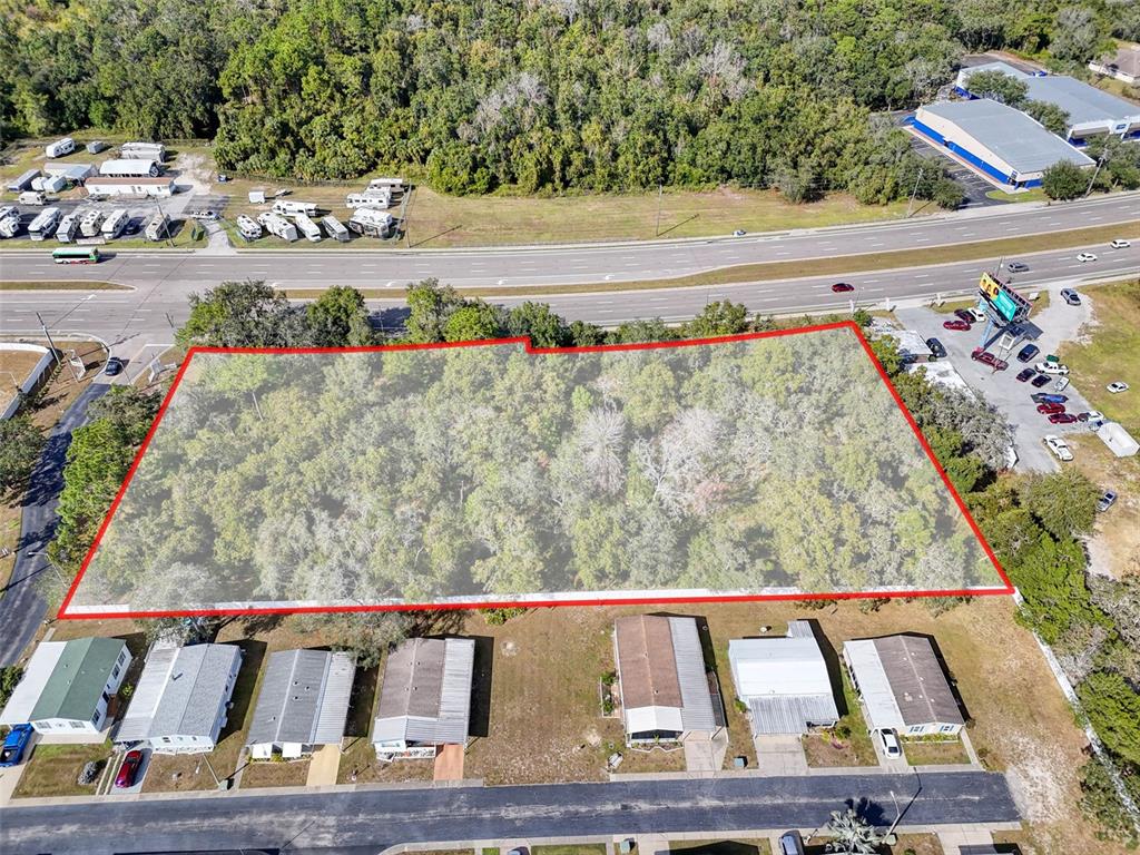 An aerial view shows a rectangular, wooded lot outlined in red next to a highway — 10780 STATE ROAD 52, HUDSON, FL