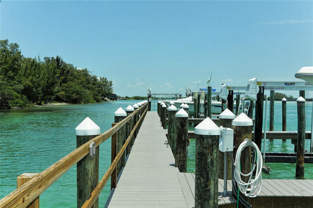 A white Sailfish motorboat with two people on board travels past a wooden bridge — 6040 BOCA GRANDE CAUSEWAY UNIT 5, BOCA GRANDE, FL