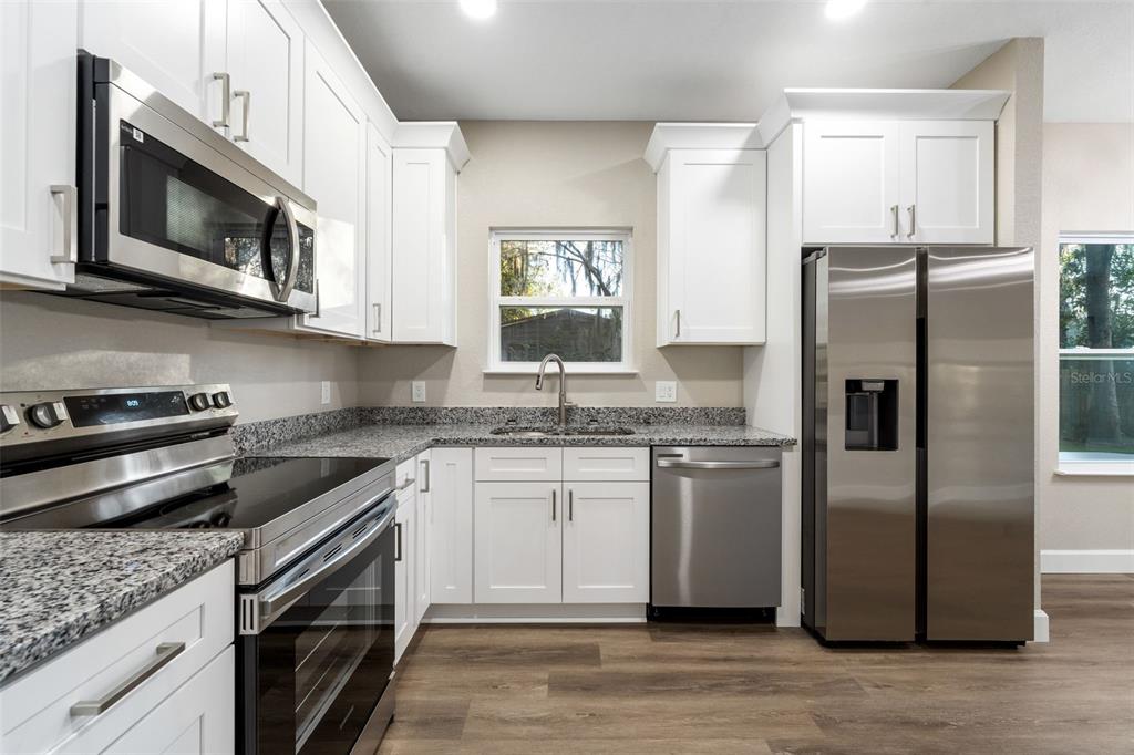 A kitchen with white cabinets, stainless steel appliances, and granite countertops — 2016 NE 3RD AVENUE, GAINESVILLE, FL