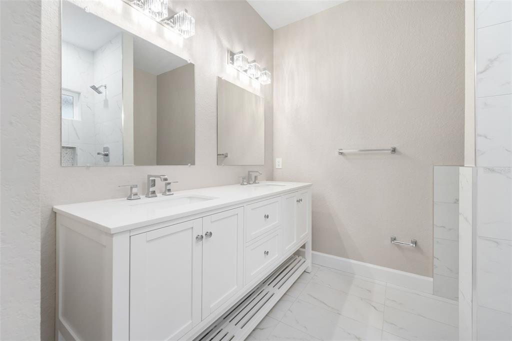 A bathroom features a white double vanity, two mirrors, and light-colored tile flooring — 2016 NE 3RD AVENUE, GAINESVILLE, FL