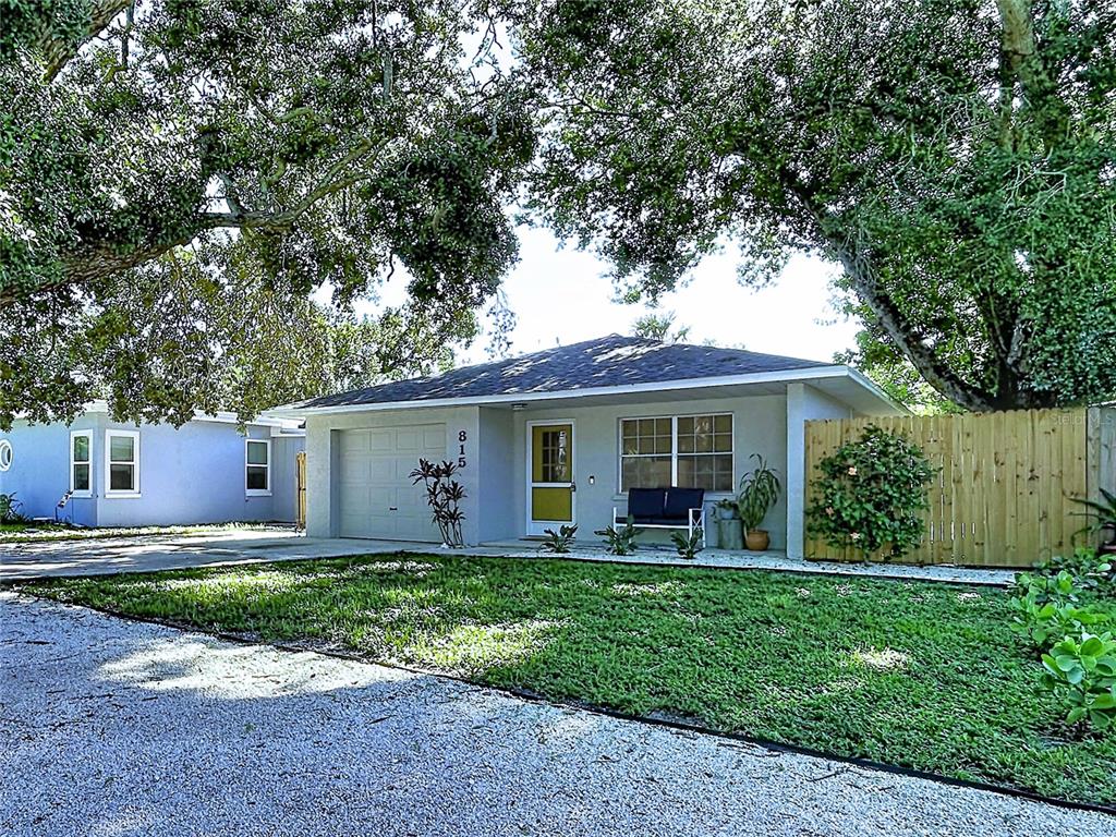 A single-story house with a gray exterior, a garage, and a gravel driveway under large trees — 815 35TH STREET W, BRADENTON, FL