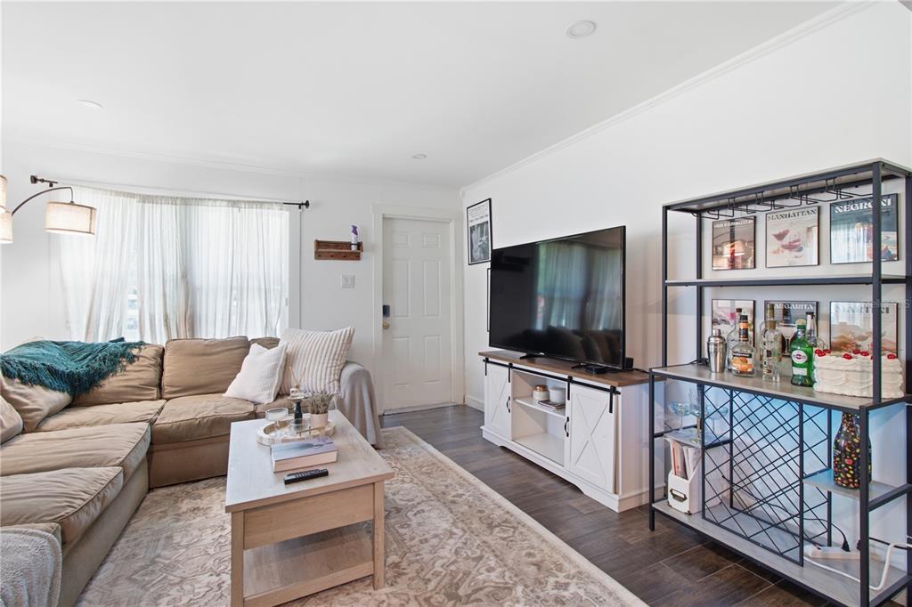 A living room features a tan sectional sofa, a television on a white console, and a bar — 5552 CRISSMAN DRIVE N, ST PETERSBURG, FL