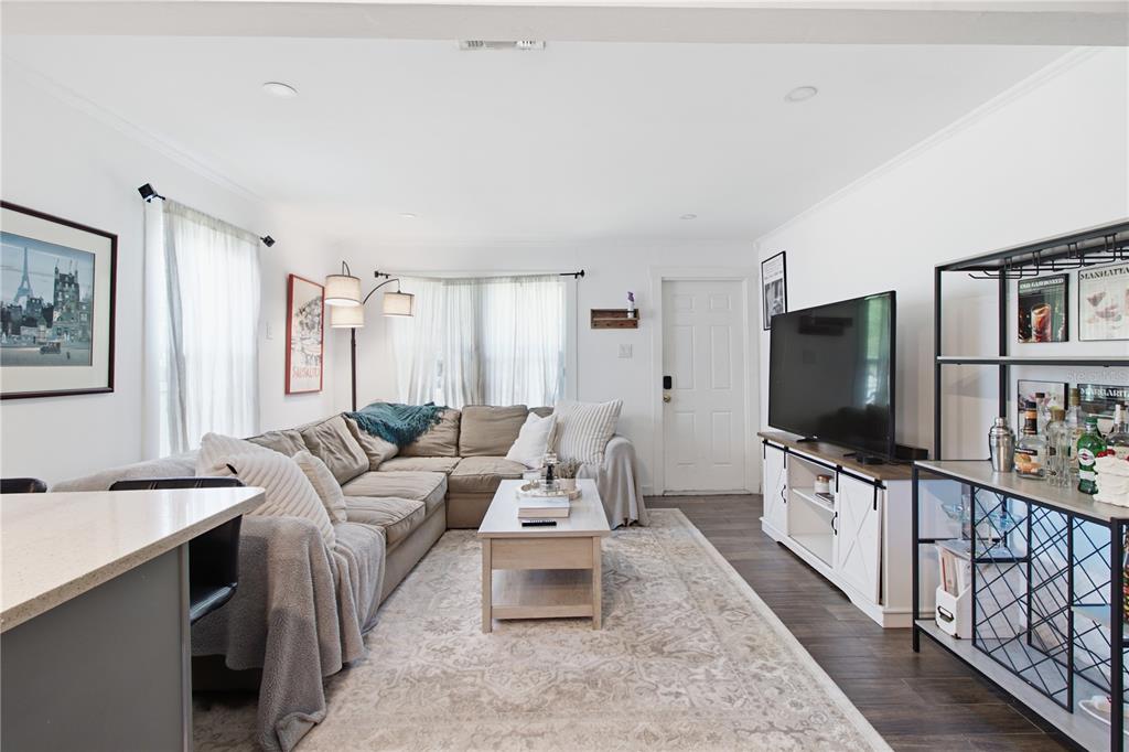 A living room features a sectional sofa, a coffee table, a television, and a bar cart — 5552 CRISSMAN DRIVE N, ST PETERSBURG, FL