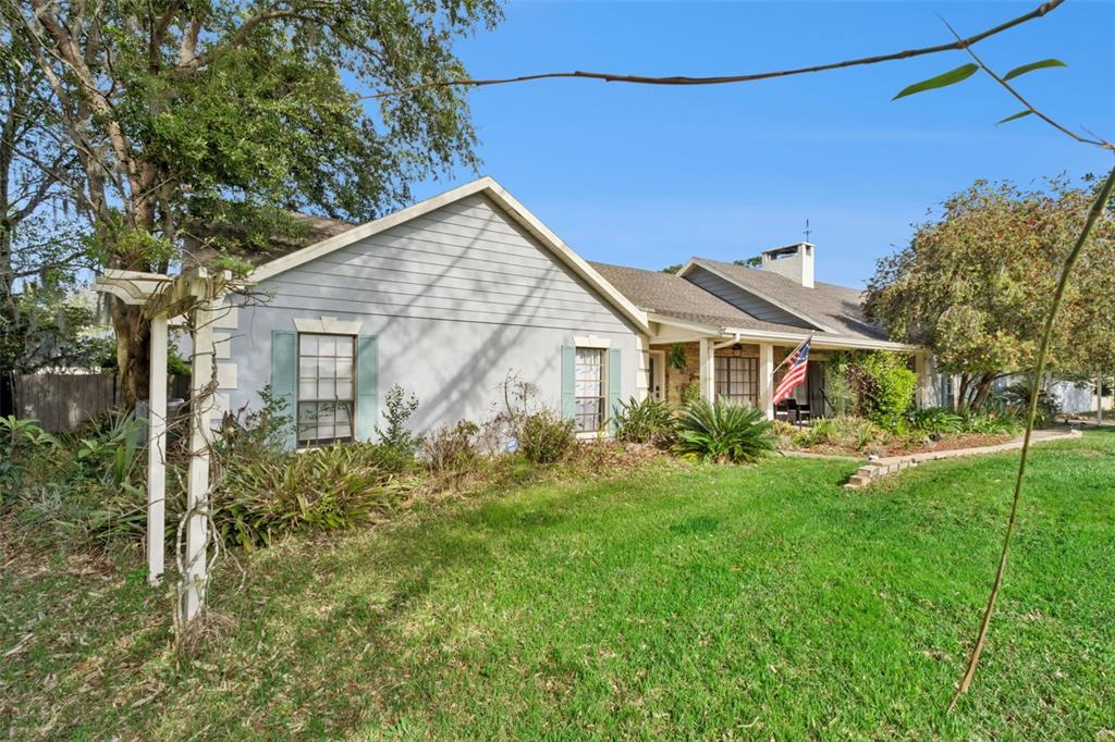 A single-story house with light gray siding, green shutters, and a front yard with trees — 2002 FAIRWAY DRIVE, EUSTIS, FL