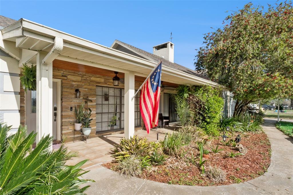The exterior of a single-story house features a stone facade, a covered porch, and landscaping — 2002 FAIRWAY DRIVE, EUSTIS, FL