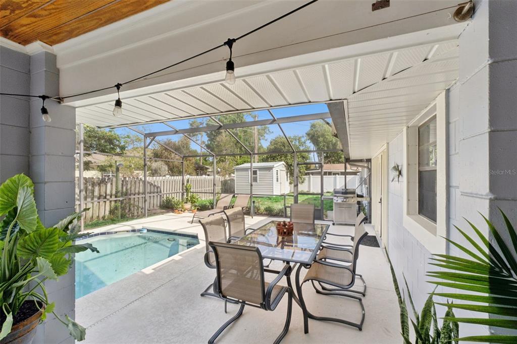 A covered patio features a dining set, a swimming pool, and a screened-in backyard area — 2002 FAIRWAY DRIVE, EUSTIS, FL