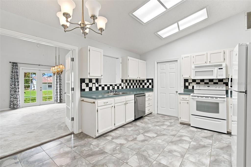 A kitchen with white cabinets, a black and white checkered backsplash, and gray tile flooring — 863 WISTERIA PLACE, TAVARES, FL