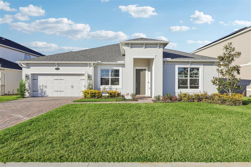 A single-story house with a white stucco exterior, a two-car garage, and a front lawn — 710 CREEPING FIG STREET, APOPKA, FL