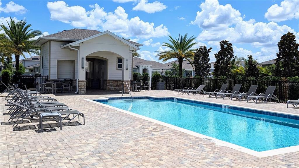 A rectangular swimming pool sits on a paved deck next to a covered clubhouse building — 2769 FRANKLIN ROAD, ST CLOUD, FL