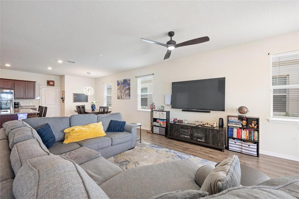 A living room features a gray sectional sofa, a large television, and wood-look flooring — 2769 FRANKLIN ROAD, ST CLOUD, FL