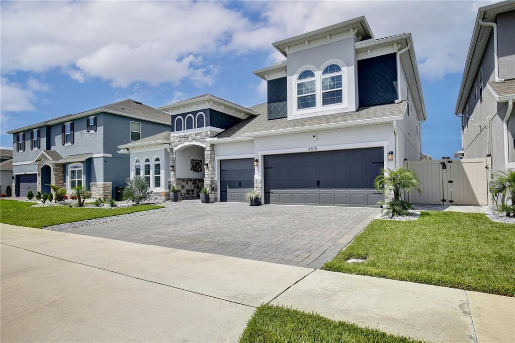 A two-story suburban house with a gray garage, stone accents, and a paved driveway — 4515 LIONS GATE AVENUE, CLERMONT, FL