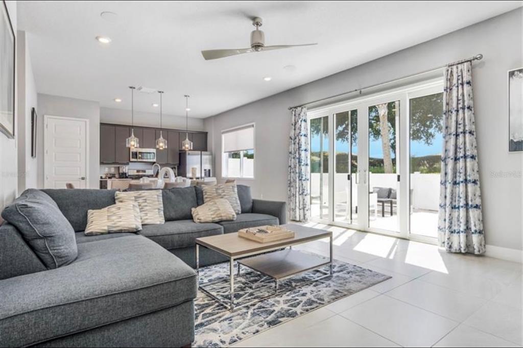 A living room with a grey sectional sofa, coffee table, and sliding glass doors to a patio — 7760 SANDY RIDGE DRIVE UNIT 108, REUNION, FL
