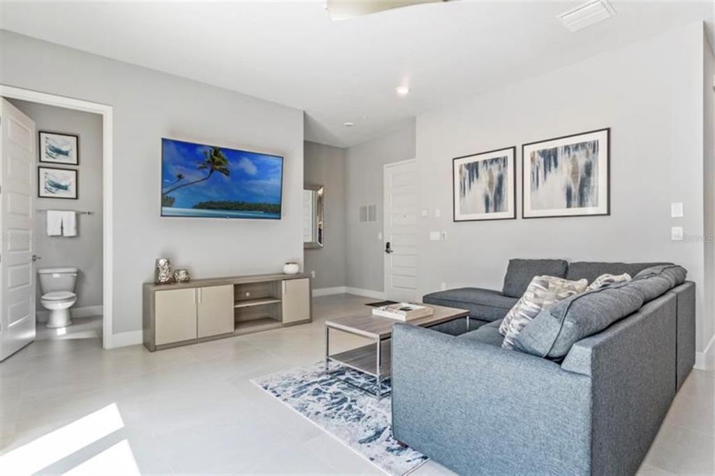 A living room with a grey sectional sofa, coffee table, television, and an adjacent bathroom — 7760 SANDY RIDGE DRIVE UNIT 108, REUNION, FL