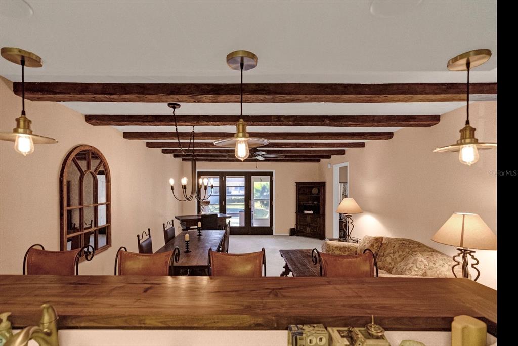 A kitchen with wood cabinets, white appliances, and exposed ceiling beams overlooking a dining area — 2465 NORTHSIDE DRIVE UNIT 1808, CLEARWATER, FL