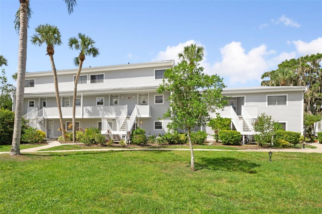 A two-story apartment building with light gray siding, white railings, and palm trees — 125 RIVER BEND PLACE UNIT D, WELAKA, FL