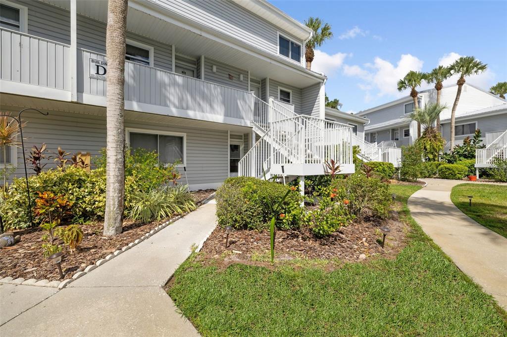A two-story apartment building with light gray siding features an exterior staircase and landscaping — 125 RIVER BEND PLACE UNIT D, WELAKA, FL