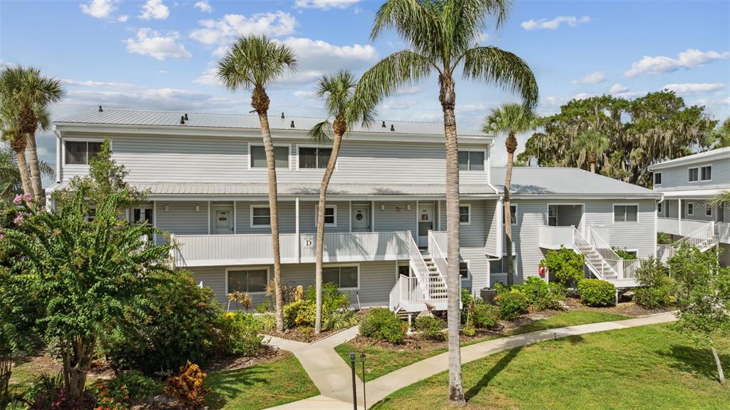 A two-story apartment building with light gray siding, a metal roof, and palm trees — 125 RIVER BEND PLACE UNIT D, WELAKA, FL