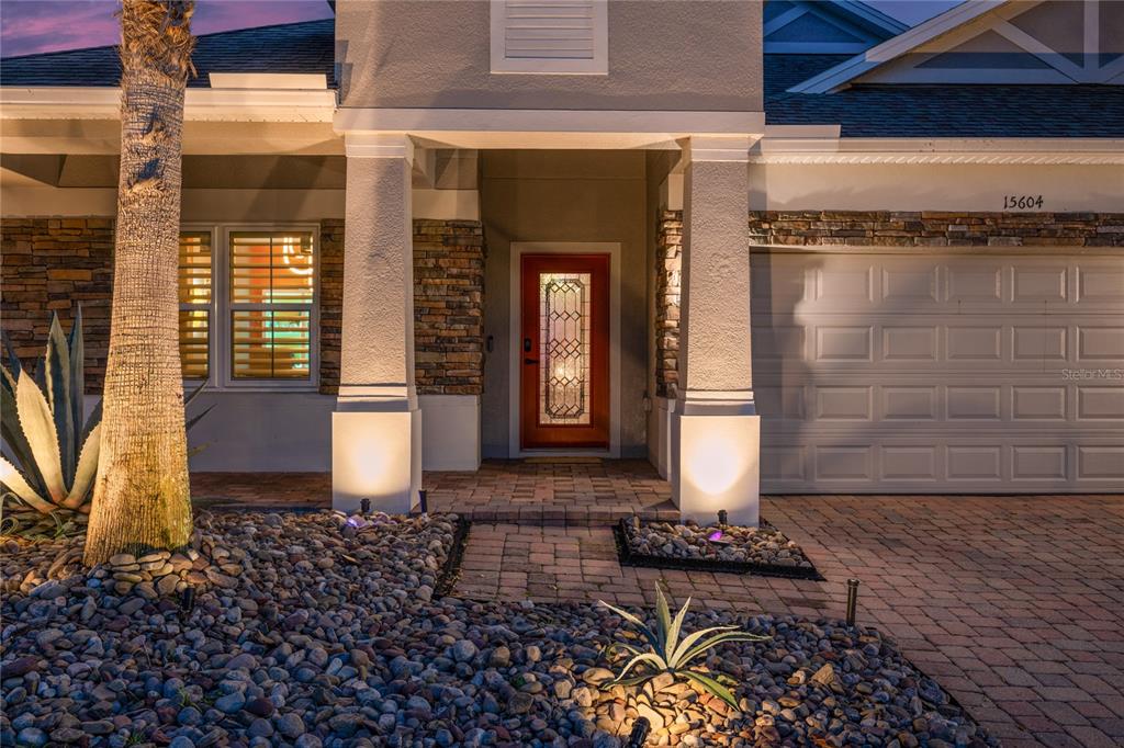 A single-story house with a stone facade, a paved driveway, and a manicured lawn — 15604 GRANLUND STREET, WINTER GARDEN, FL