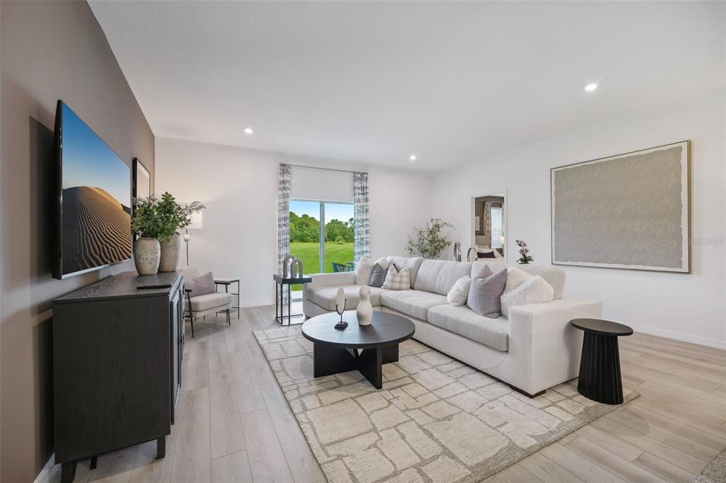 A living room features a sectional sofa, a round coffee table, and a wall-mounted television — 1092 CLAY BOULEVARD, TAVARES, FL