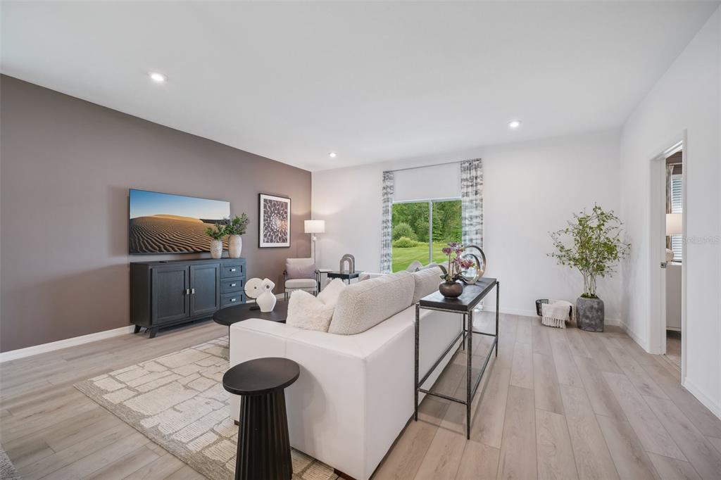 A living room features a white sofa, a dark media console, and light wood flooring — 1092 CLAY BOULEVARD, TAVARES, FL