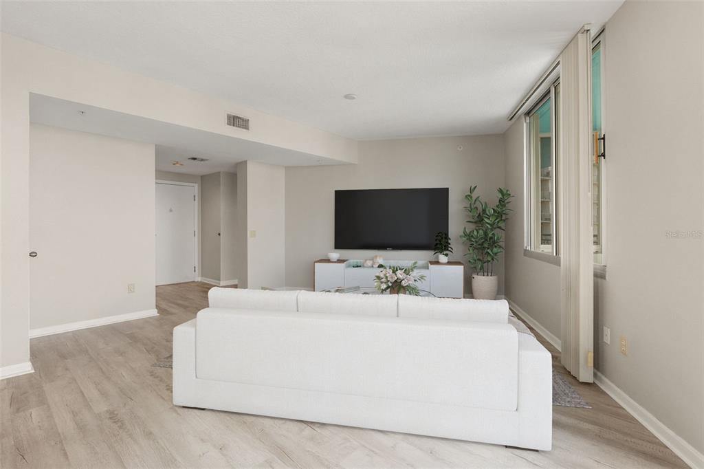 A living room features a white sofa, a television on a console, and light wood flooring — 322 E CENTRAL BOULEVARD UNIT 1910, ORLANDO, FL