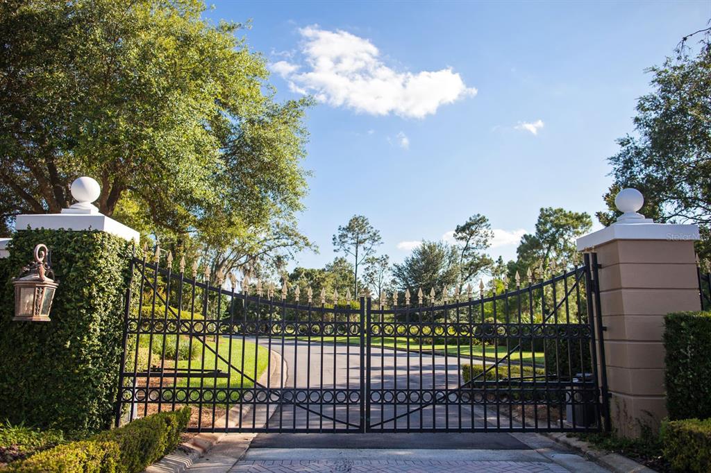 A black metal gate stands between two stone pillars topped with white spheres — LOT 36, CROMWELL ROAD, ORLANDO, FL