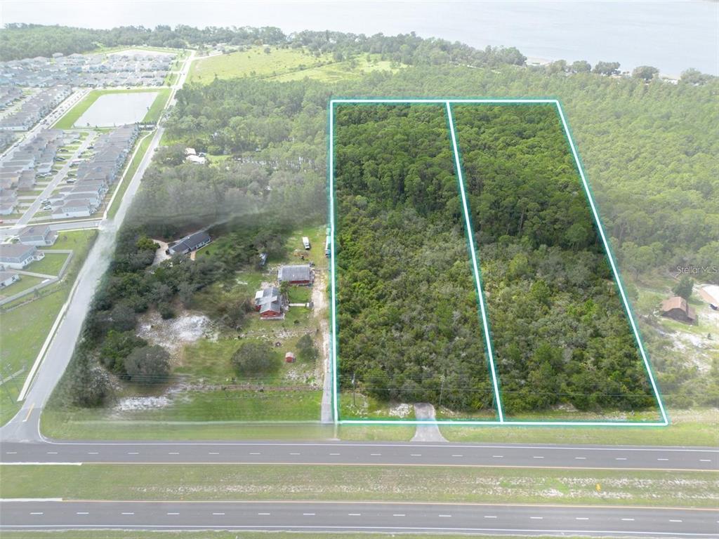 An aerial view shows two adjacent wooded lots bordering a multi-lane highway — 0 IRLO BRONSON MEMORIAL HIGHWAY, ST CLOUD, FL