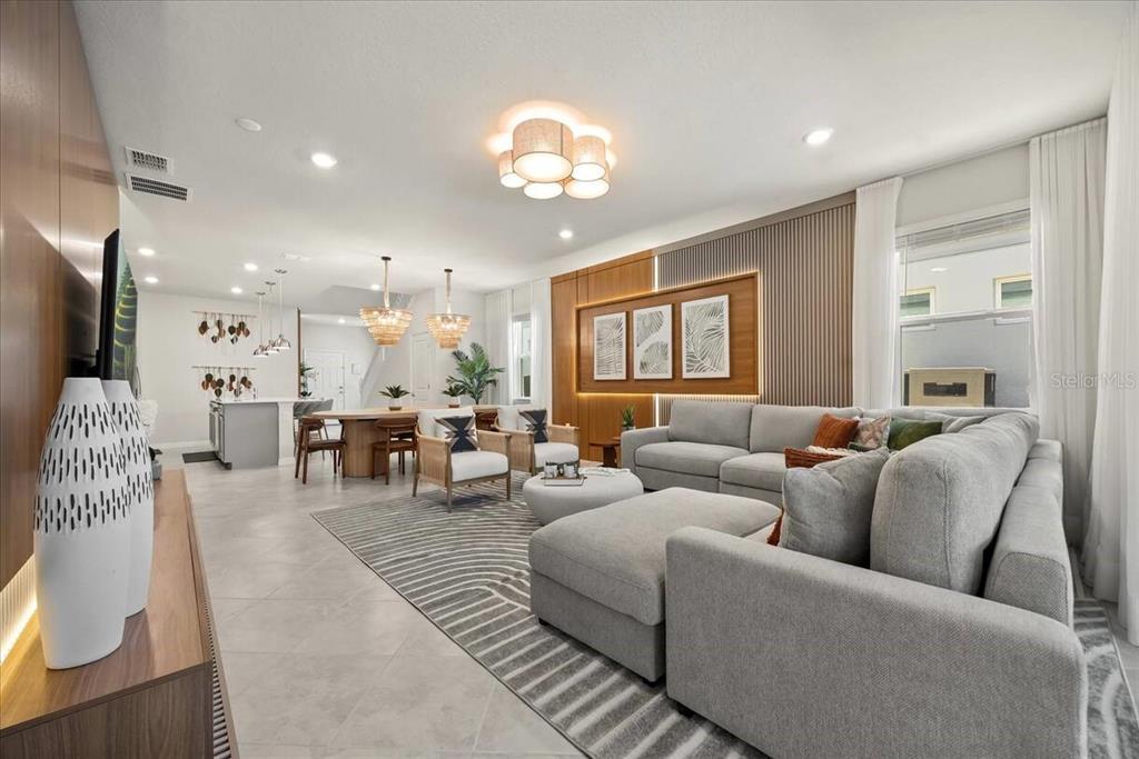 A modern open-concept living and dining area features a large sectional sofa and tile flooring — 15952 CAPE CORAL LOOP, CLERMONT, FL