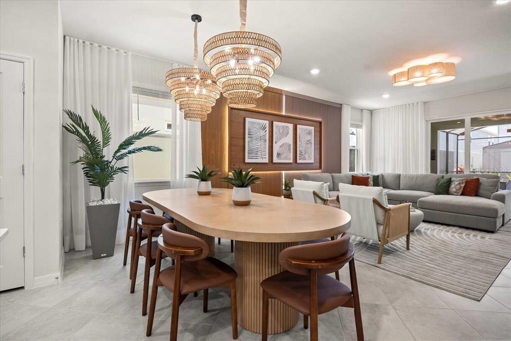 A dining area with a wooden oval table and rattan chandeliers sits beside a living room — 15952 CAPE CORAL LOOP, CLERMONT, FL