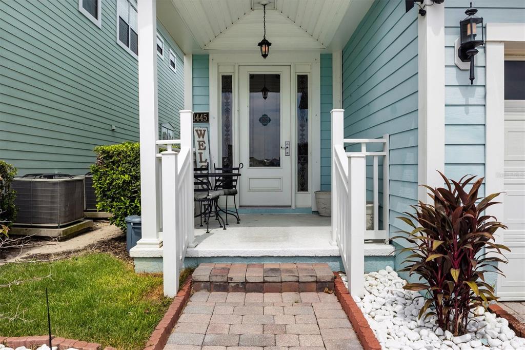 A light blue house features a white front door, a covered porch, and brick walkway — 1445 FAIRVIEW CIRCLE, KISSIMMEE, FL