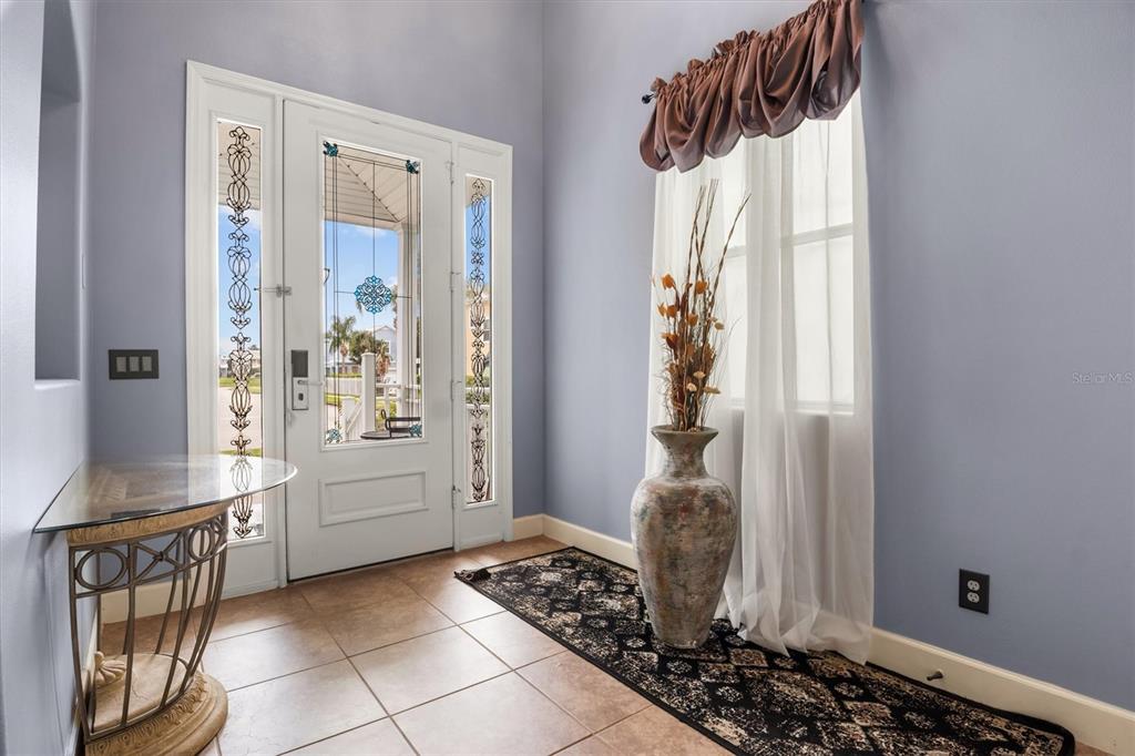 An entryway features a glass-paneled door, tiled floors, a console table, and a decorative vase — 1445 FAIRVIEW CIRCLE, KISSIMMEE, FL