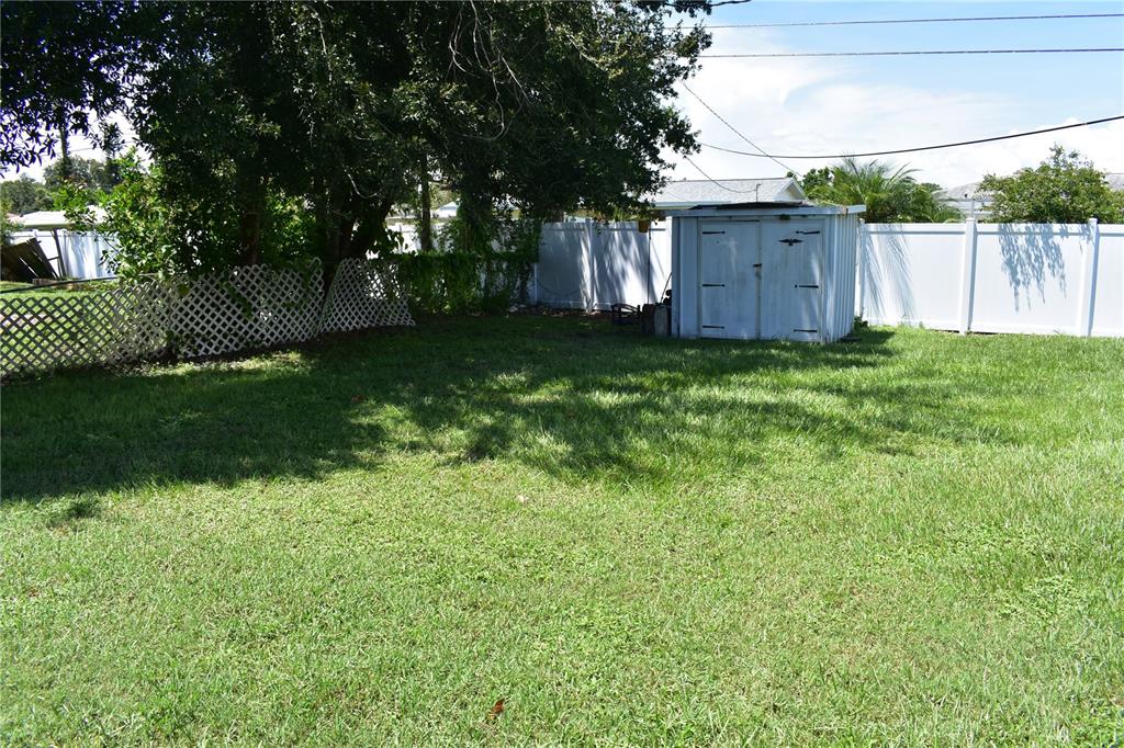 A grassy backyard features a white storage shed and a white lattice fence — 3602 17TH AVENUE W, BRADENTON, FL