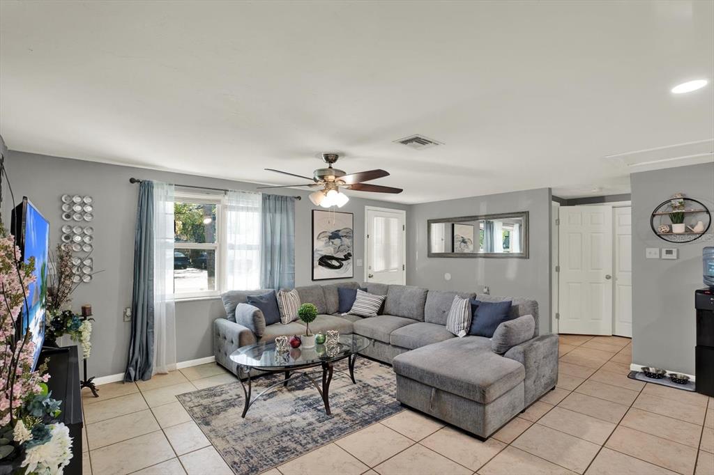 A living room features a gray sectional sofa, a glass coffee table, and tile flooring — 5609 QUIST DRIVE, PORT RICHEY, FL