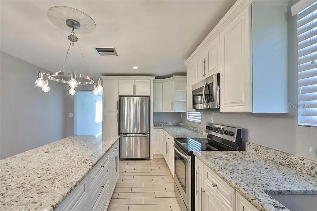 A kitchen features white cabinets, granite countertops, stainless steel appliances, and a central island — 3219 W LEROY STREET, TAMPA, FL