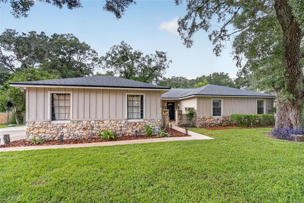 A single-story house with board-and-batten siding, a stone facade, and a large oak tree — 2070 SE 50TH TERRACE, OCALA, FL