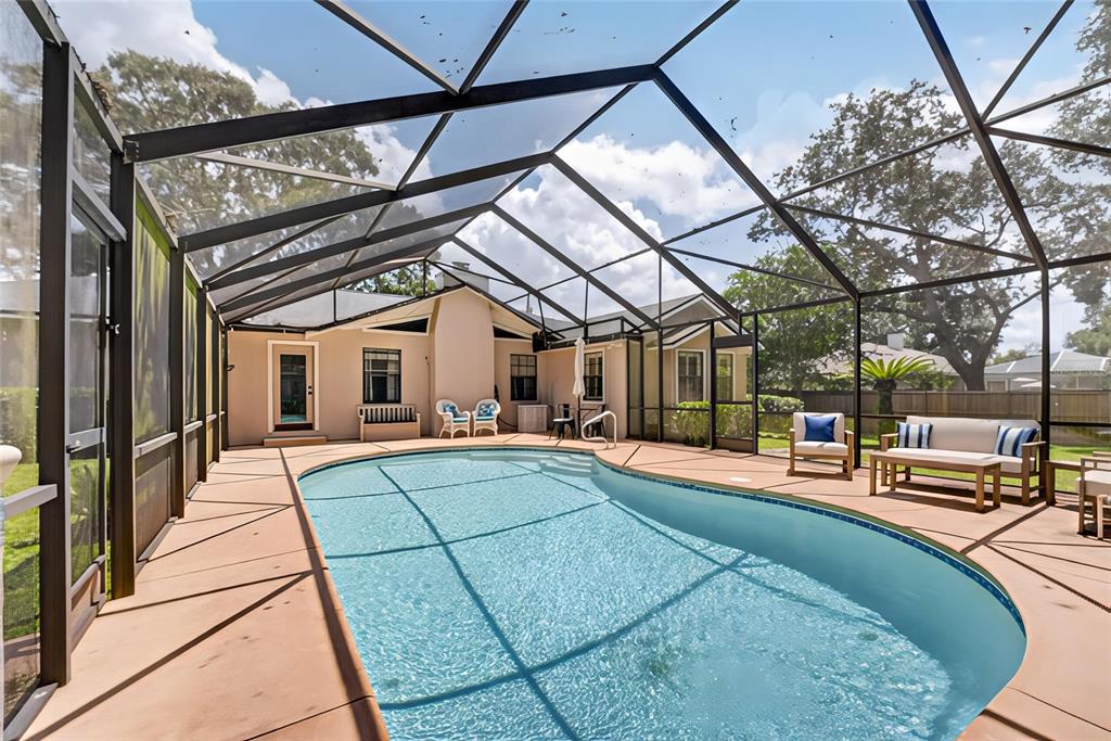 A screened-in patio features a kidney-shaped swimming pool and outdoor seating on a concrete deck — 2070 SE 50TH TERRACE, OCALA, FL