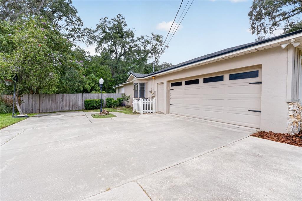 A concrete driveway leads to a two-car garage beside a house with a white fence — 2070 SE 50TH TERRACE, OCALA, FL