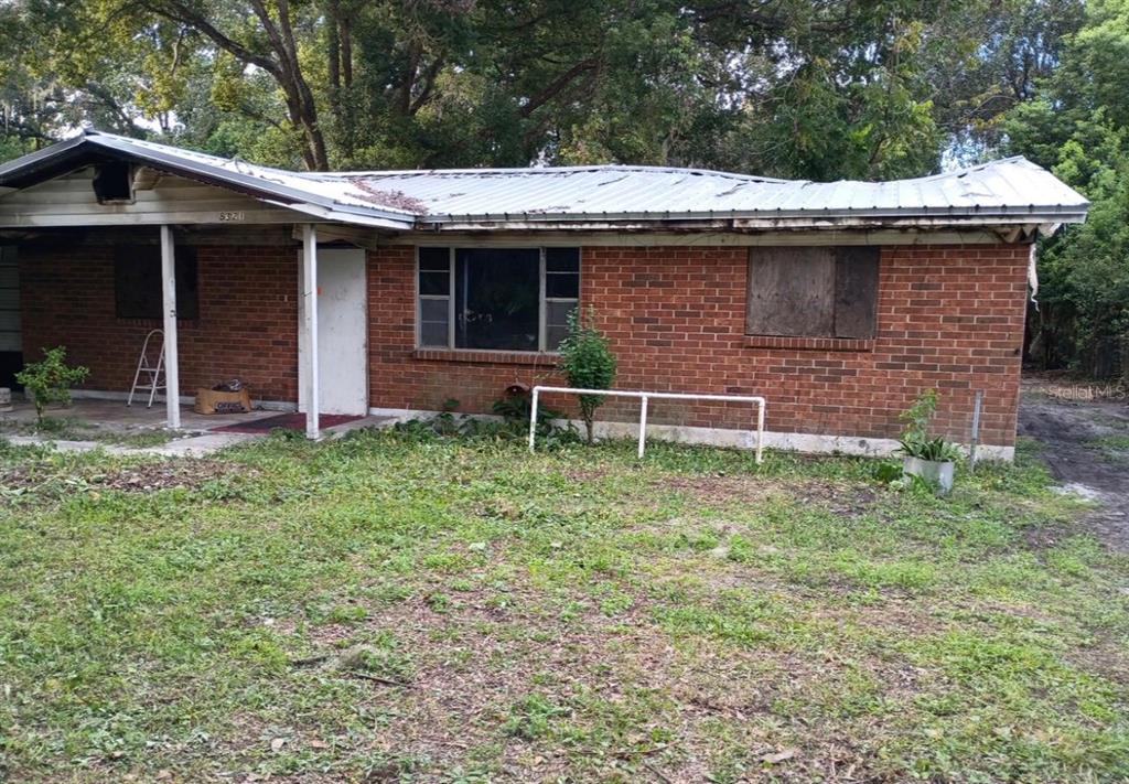 A single-story brick house with a damaged metal roof and boarded-up windows — 8321 OLD PLANK ROAD, JACKSONVILLE, FL